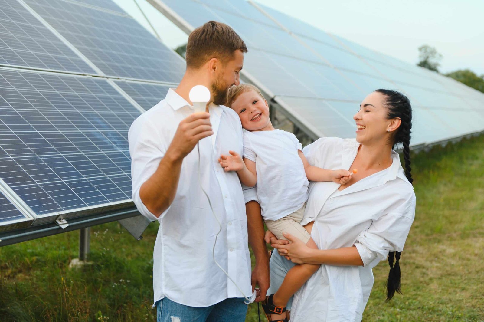 Young family of three is crouching near photovoltaic solar panel, little boy and parents